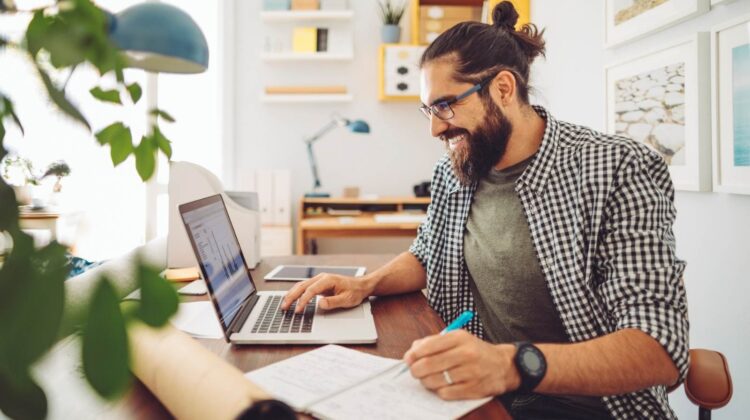 Man smiling while working on laptop