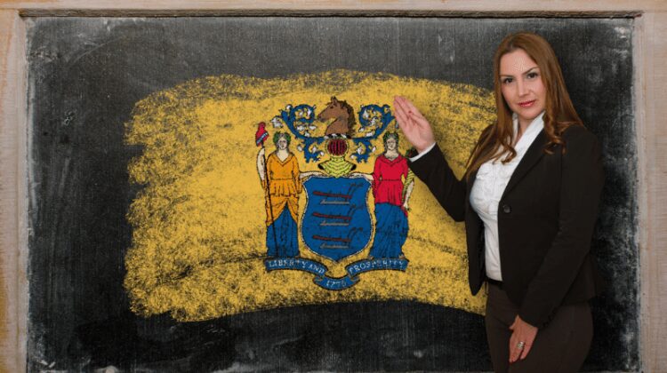 Teacher pointing to the New Jersey flag on a chalkboard