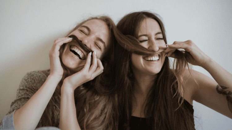 girls smiling and holding each other's hair