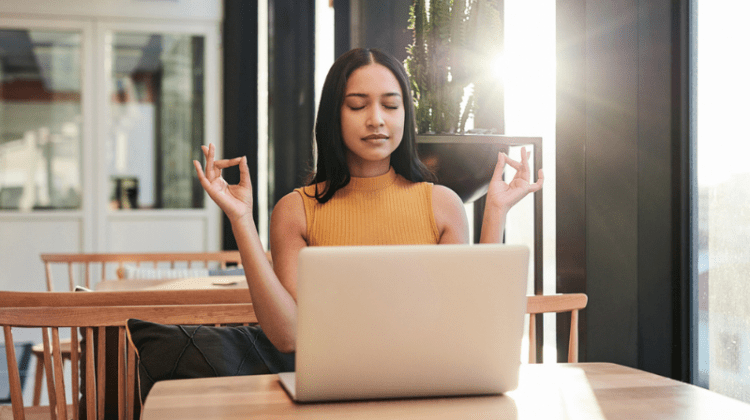 female student meditating in front of her computer