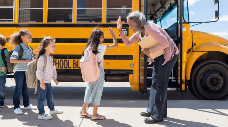 school principal high fives student getting on the bus