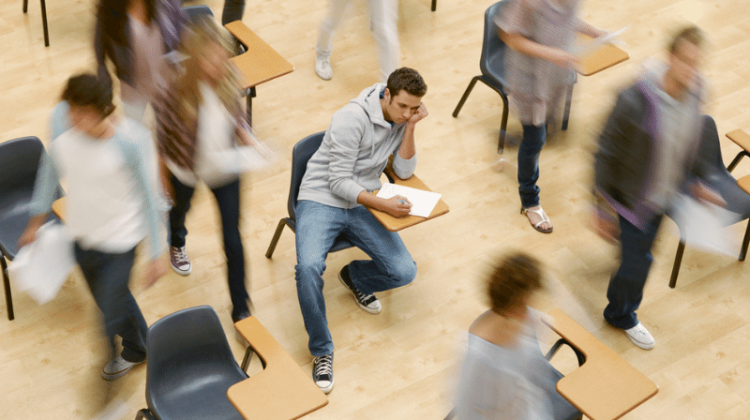 Student sits at desk while everyone around him walks out